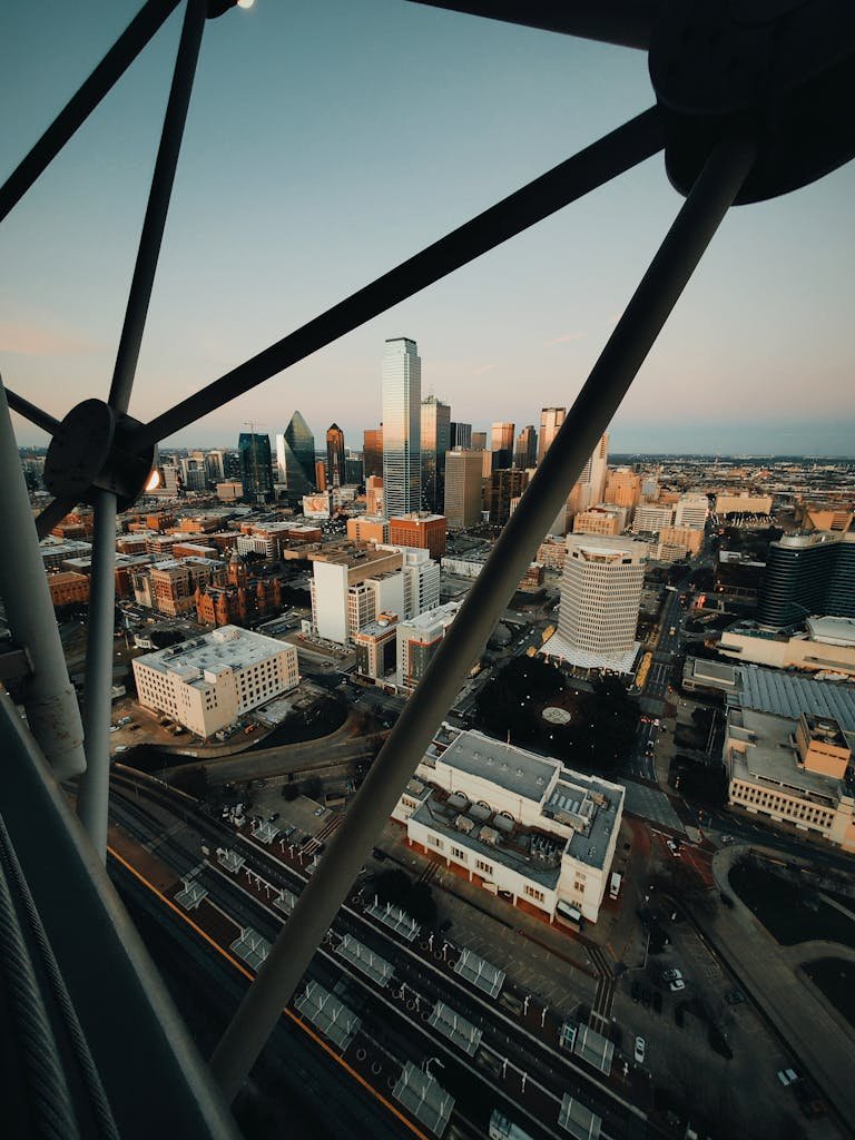 Aerial view of a bustling city skyline at sunset with modern skyscrapers and urban streets.